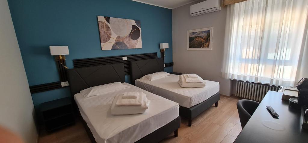 una camera d'albergo con due letti e un tavolo di Hotel Roma a Palmanova