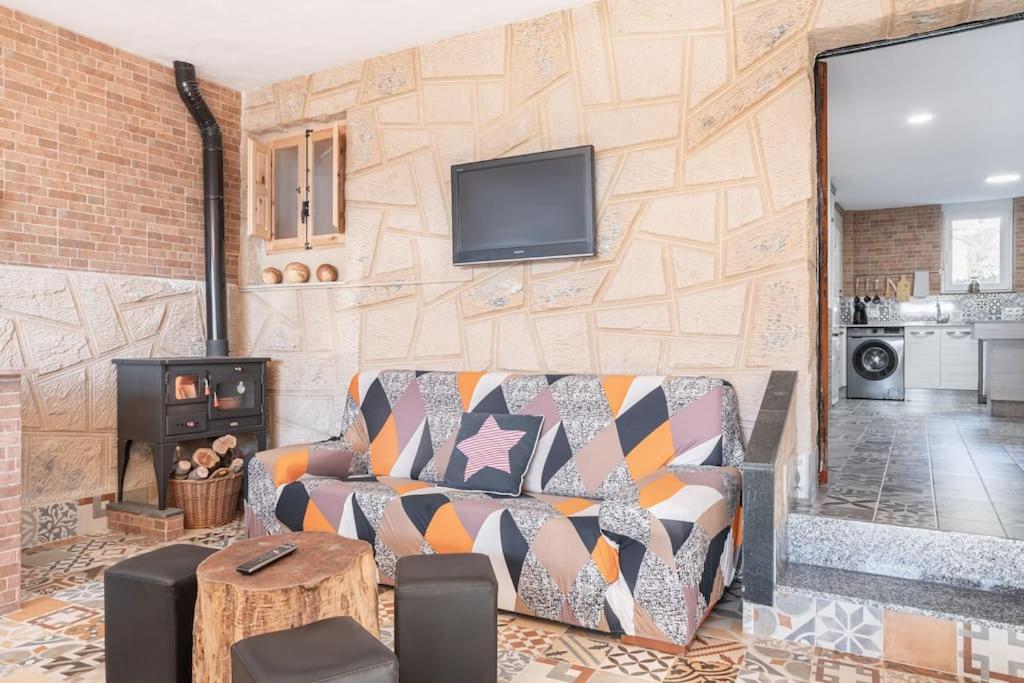 ein Wohnzimmer mit einem Sofa und einem TV an der Wand in der Unterkunft Oviedo Rural in Oviedo