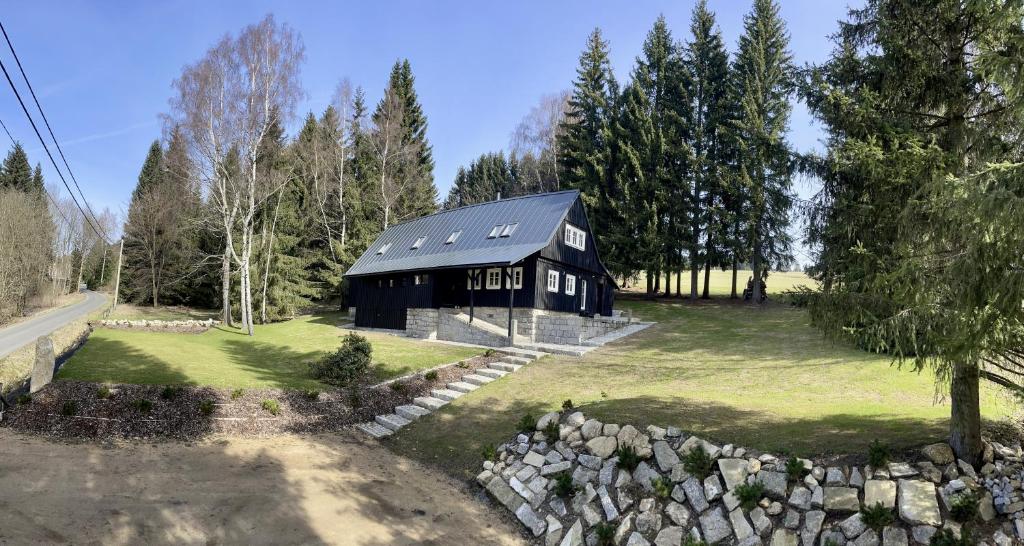 a black house with a black roof on a green field at Izerína Cottage in Horní Maxov