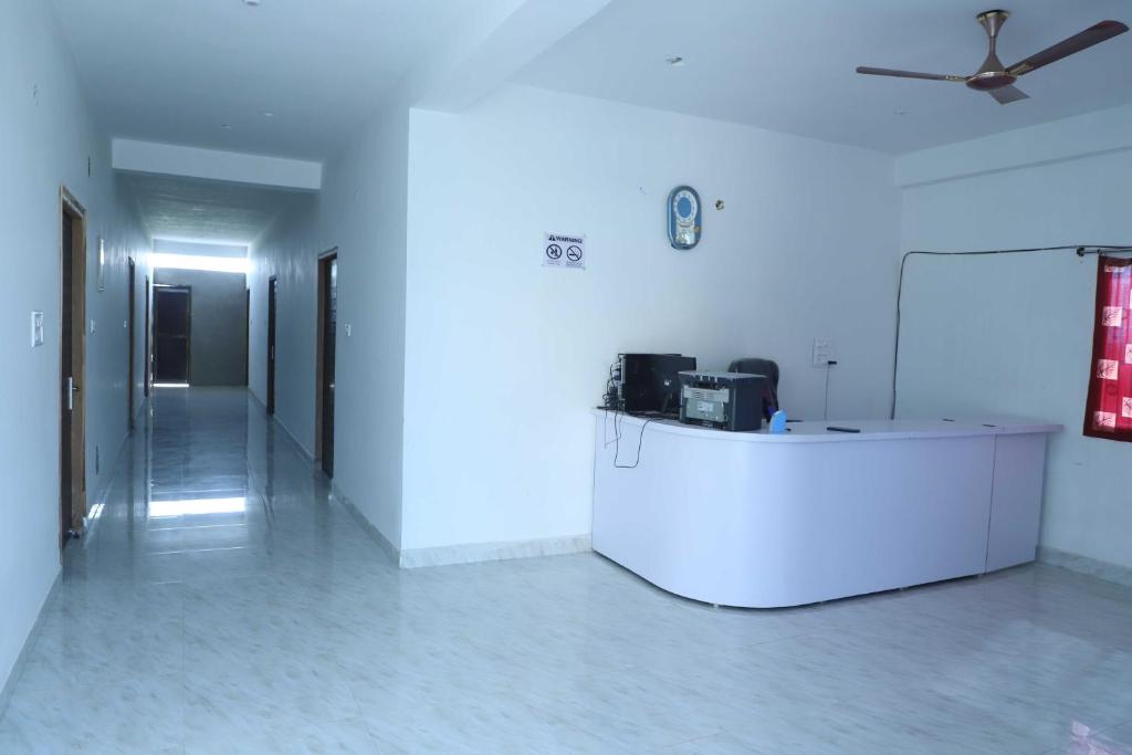 OYO Shiv guru guest house في بود جايا: غرفة بيضاء مع مروحة سقف وممر