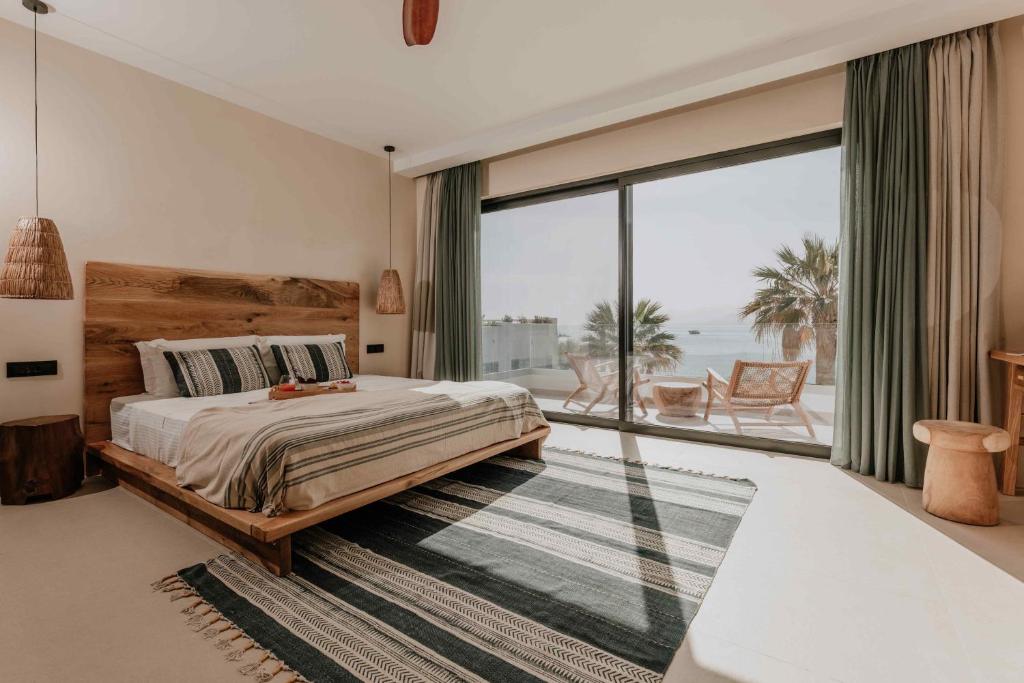a bedroom with a bed and a large window at Ostrako Beachside Suites in Agia Anna Naxos