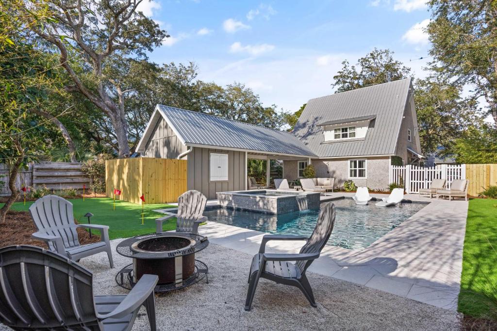 un patio trasero con piscina y sillas y una casa en Tabbystone Cottage - 4323 Fourteenth Street, en Saint Simons Island