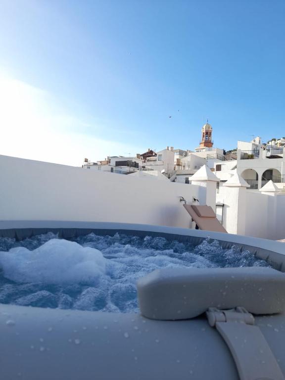 a hot tub with snow and buildings in the background at Ático El Paraíso in Cómpeta