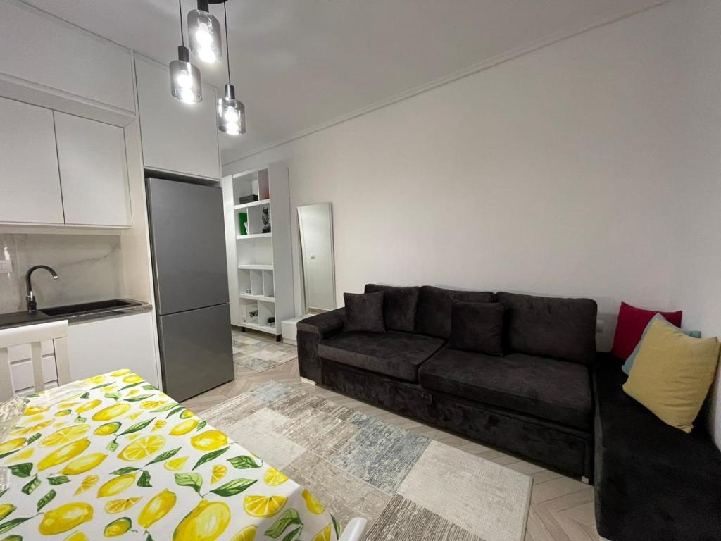 a living room with a black couch and a kitchen at RIAN GUEST HOUSE in Sarandë