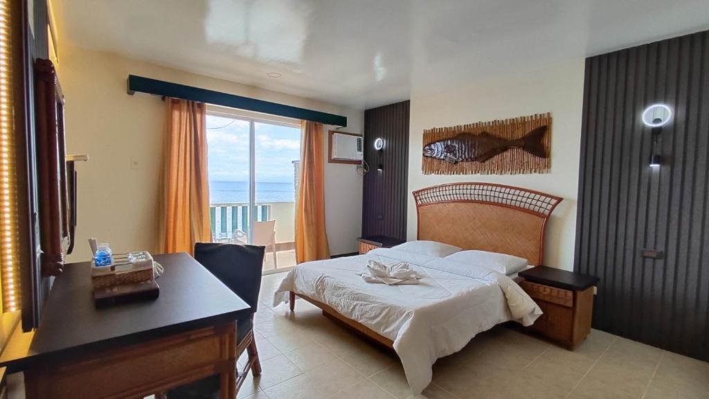 a bedroom with a bed and a desk and a window at Eagle Point Beach and Dive Resort in Mabini