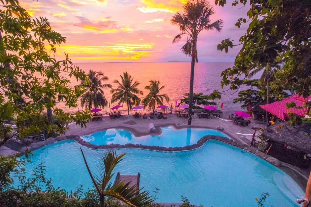 a pool at the beach with a sunset in the background at Eagle Point Beach and Dive Resort in Mabini