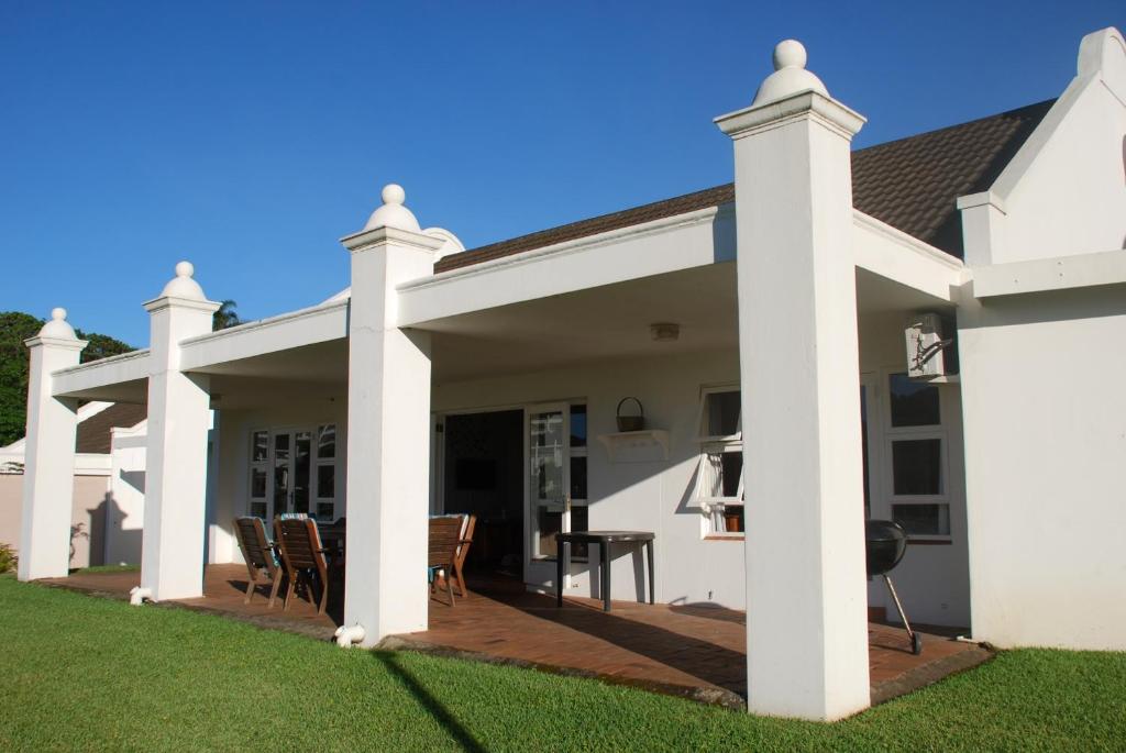 ein großes weißes Haus mit einer Terrasse in der Unterkunft Villa Arroyo, Estuary Estate, Port Edward in Port Edward