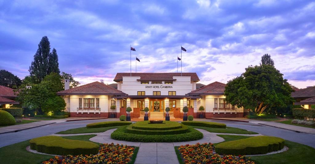 Un grand bâtiment blanc avec des drapeaux en haut dans l'établissement Hyatt Hotel Canberra - A Park Hyatt Hotel, à Canberra