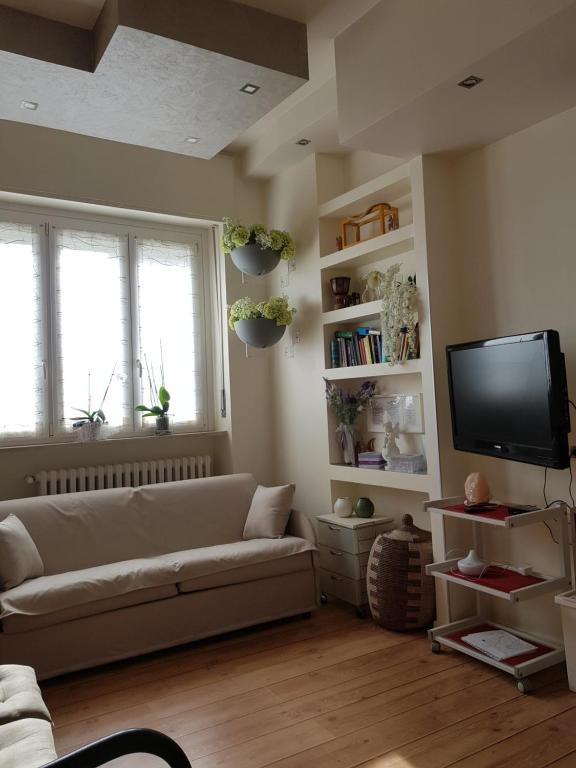 uma sala de estar com um sofá e uma televisão de ecrã plano em Langhe Beauty Apartament Experience 2 "wine" em Alba