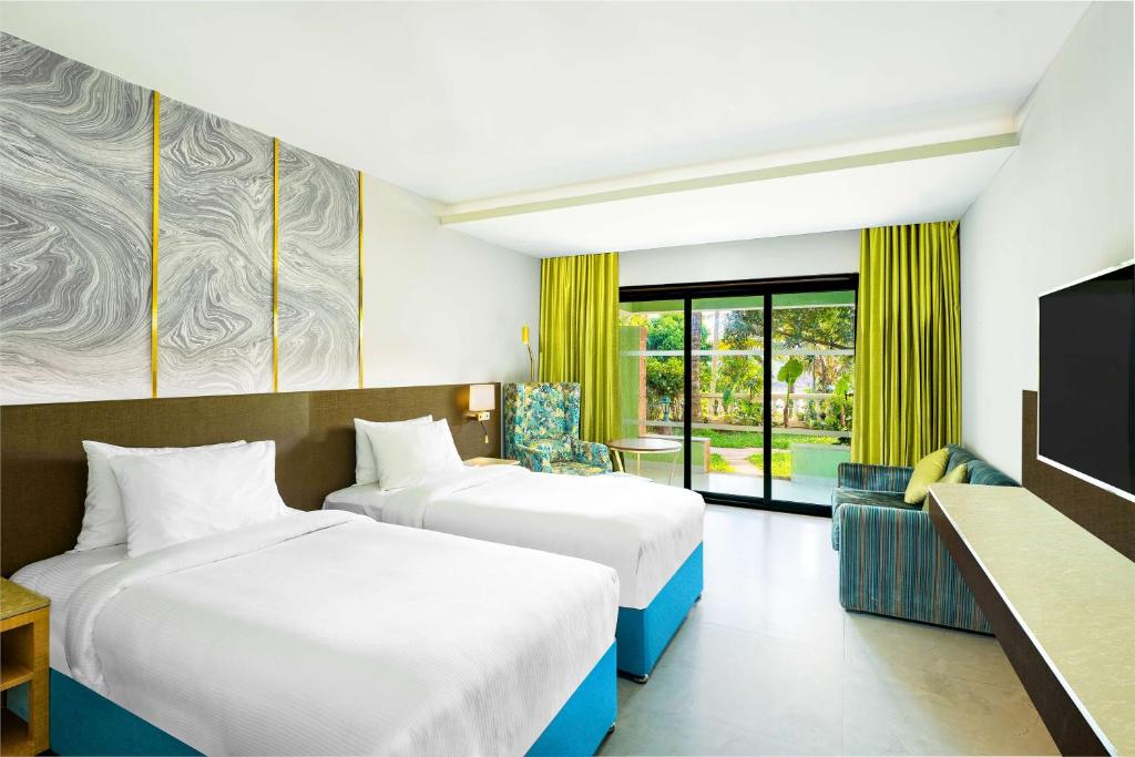 a hotel room with two beds and a television at DoubleTree by Hilton Hotel Goa - Arpora - Baga in Baga