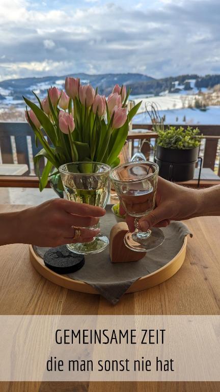 a table with two glasses and flowers on a table at Ferienwohnung Alpenflair mit Pool und Sauna & direkt am Skilift in Missen-Wilhams