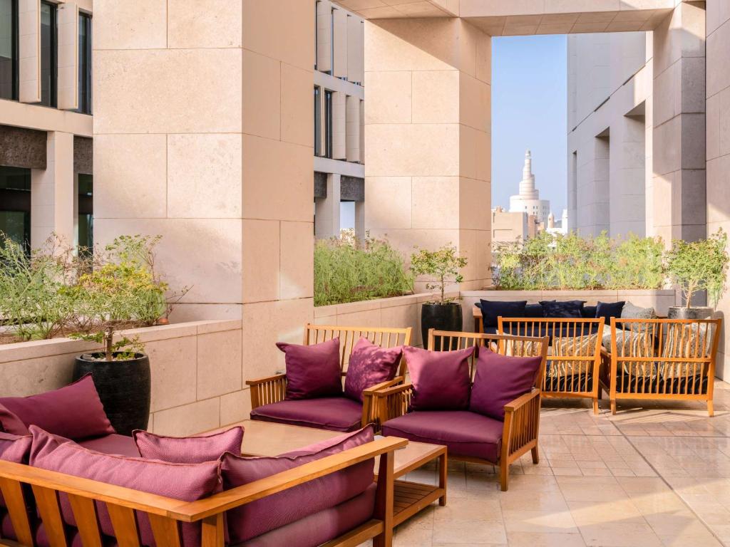 a patio with purple cushioned chairs on a building at Alwadi Hotel Doha - MGallery Collection in Doha