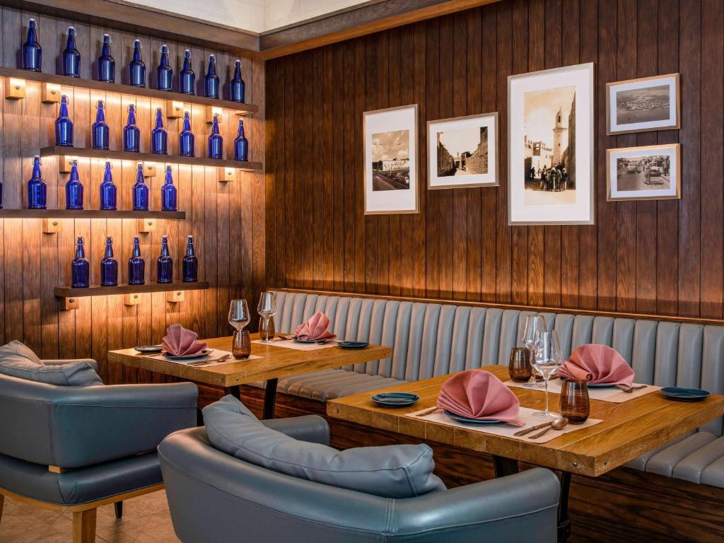 a restaurant with two tables and blue bottles on the wall at Alwadi Hotel Doha - MGallery Collection in Doha