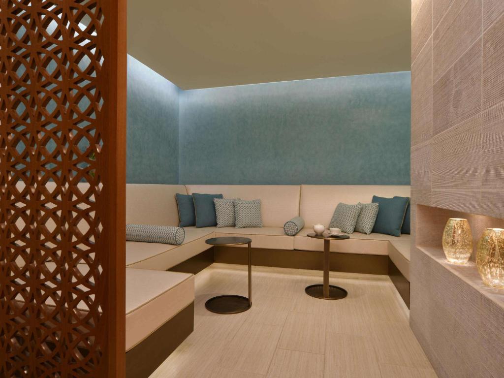 a living room with a couch with blue pillows at Alwadi Hotel Doha - MGallery Collection in Doha