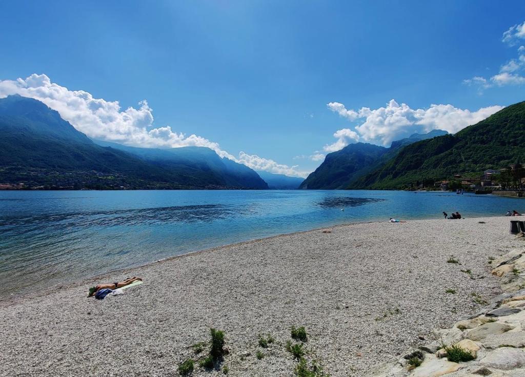 a person laying on a beach next to a body of water at Rossi Lake Family in Oliveto Lario