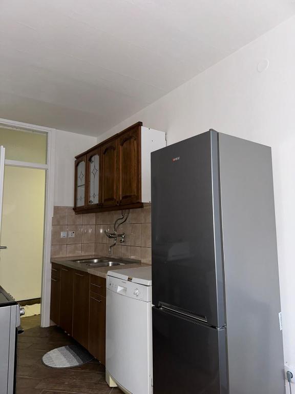 a kitchen with a black refrigerator and wooden cabinets at Rogatica Trg oslobodilaca in Rogatica