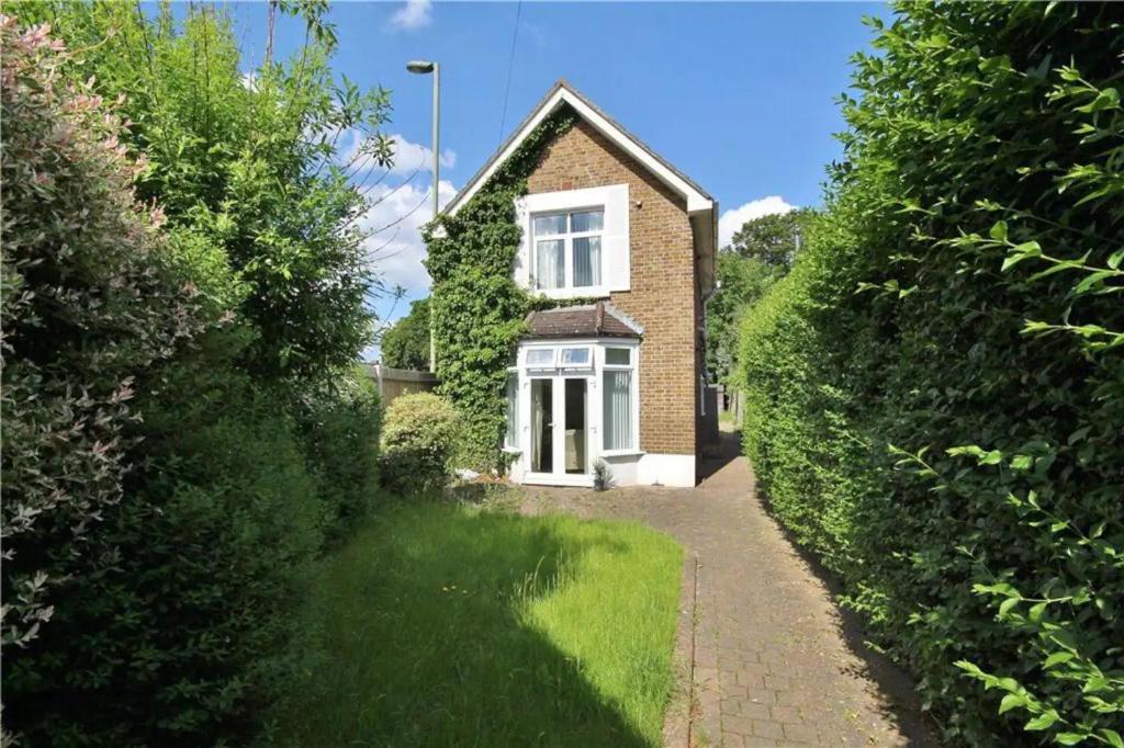 a brick house with a white window and a driveway at Detached 4-Bed House near Heathrow in Egham