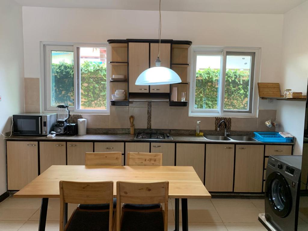 una cucina con tavolo in legno e alcune finestre di Two Bedroom House With free WiFi in Masaki a Dar es Salaam