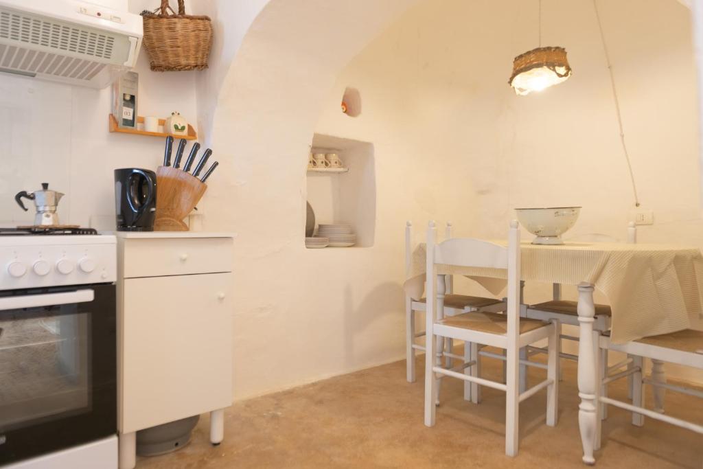 een keuken met een fornuis en een tafel met stoelen bij Trullo Nonno Marco 2.0 in Cisternino