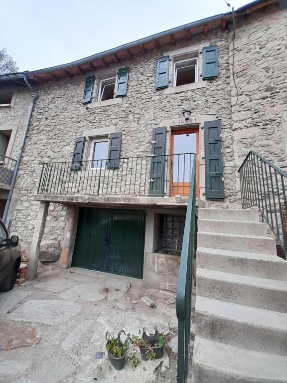 ein Steinhaus mit einer grünen Tür und Treppe in der Unterkunft Maison familiale à 10 minutes de Llivia in Angoustrine
