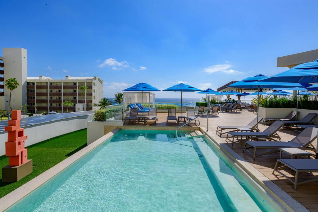 a pool on the roof of a hotel with chairs and umbrellas at Hilton Cancun Mar Caribe All-Inclusive Resort in Cancún