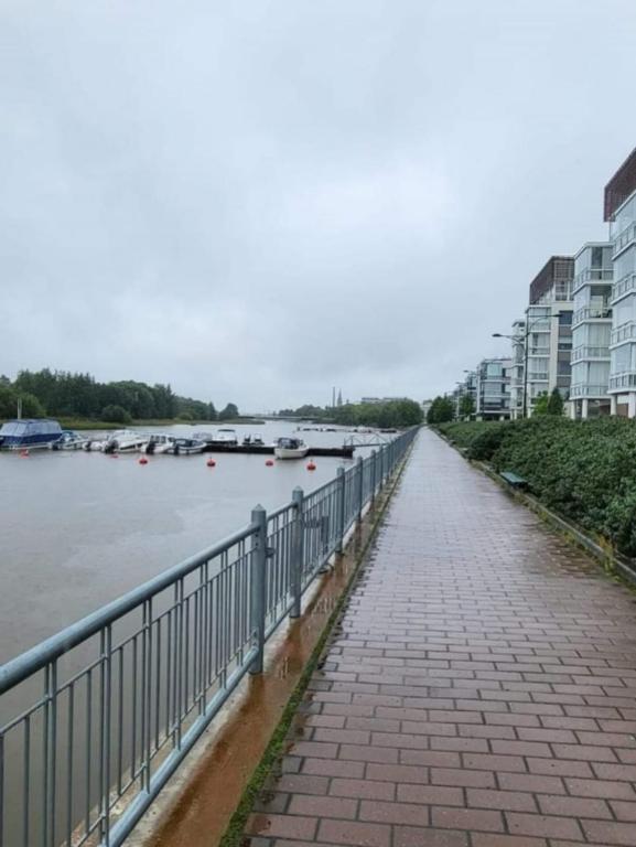 a walkway next to a river with boats in the water at Makasiiniranta in Pori
