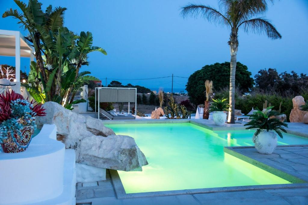 a swimming pool with a rock and palm trees at Blue Marine Guest Rooms in Lampedusa
