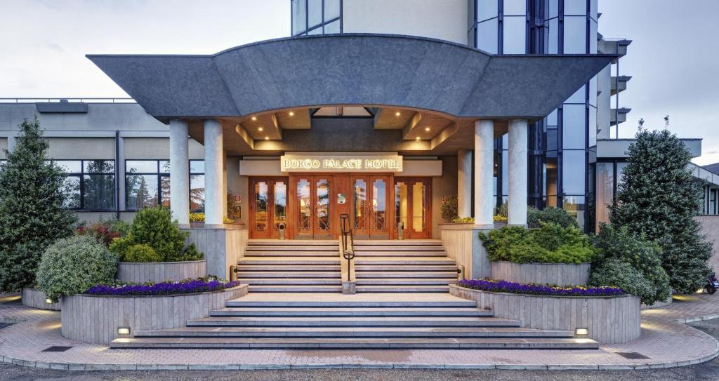 una entrada frontal a un edificio con escaleras y plantas en Borgo Palace Hotel, en Sansepolcro