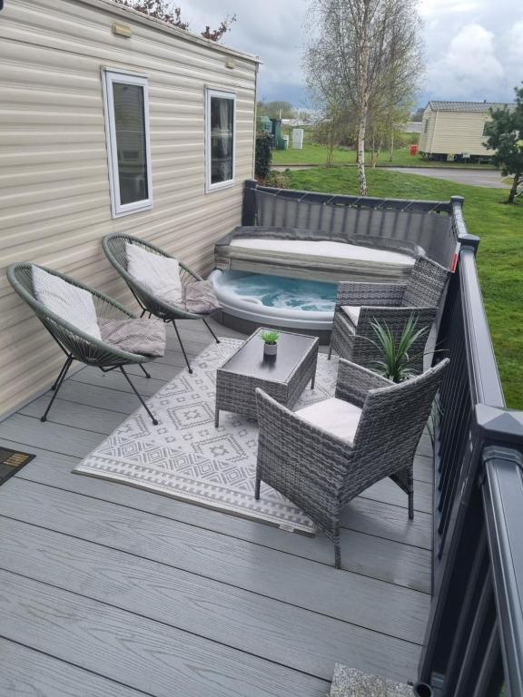 a deck with chairs and a hot tub at Luxury caravan and Tattershall lakes with private hot tub and WiFi in Tattershall