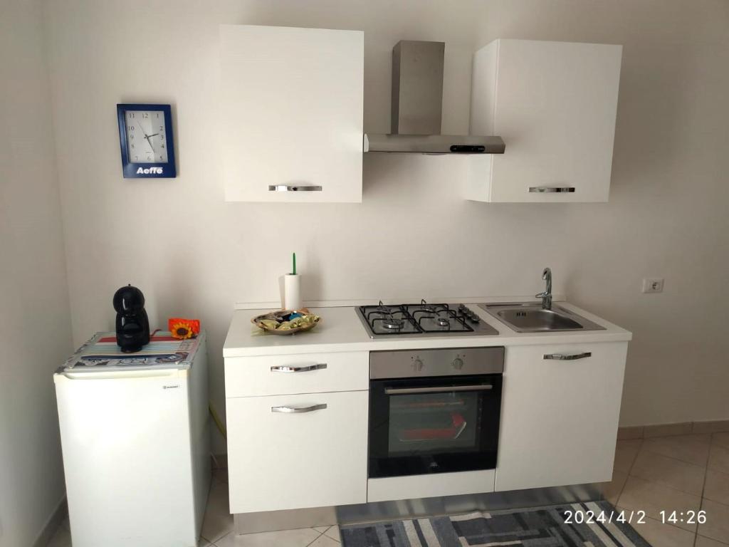 a white kitchen with a stove and a sink at Le Casette di Prissy in Rignano Flaminio