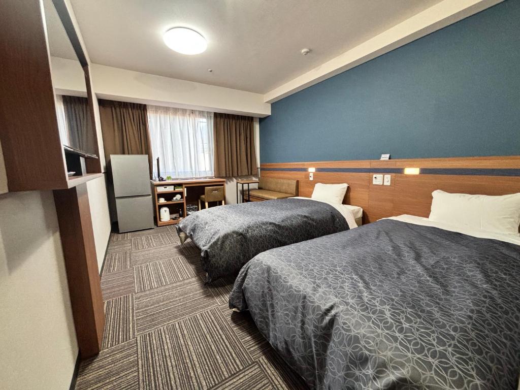 ein Hotelzimmer mit 2 Betten und einer blauen Wand in der Unterkunft Hotel 1-2-3 Kurashiki in Kurashiki