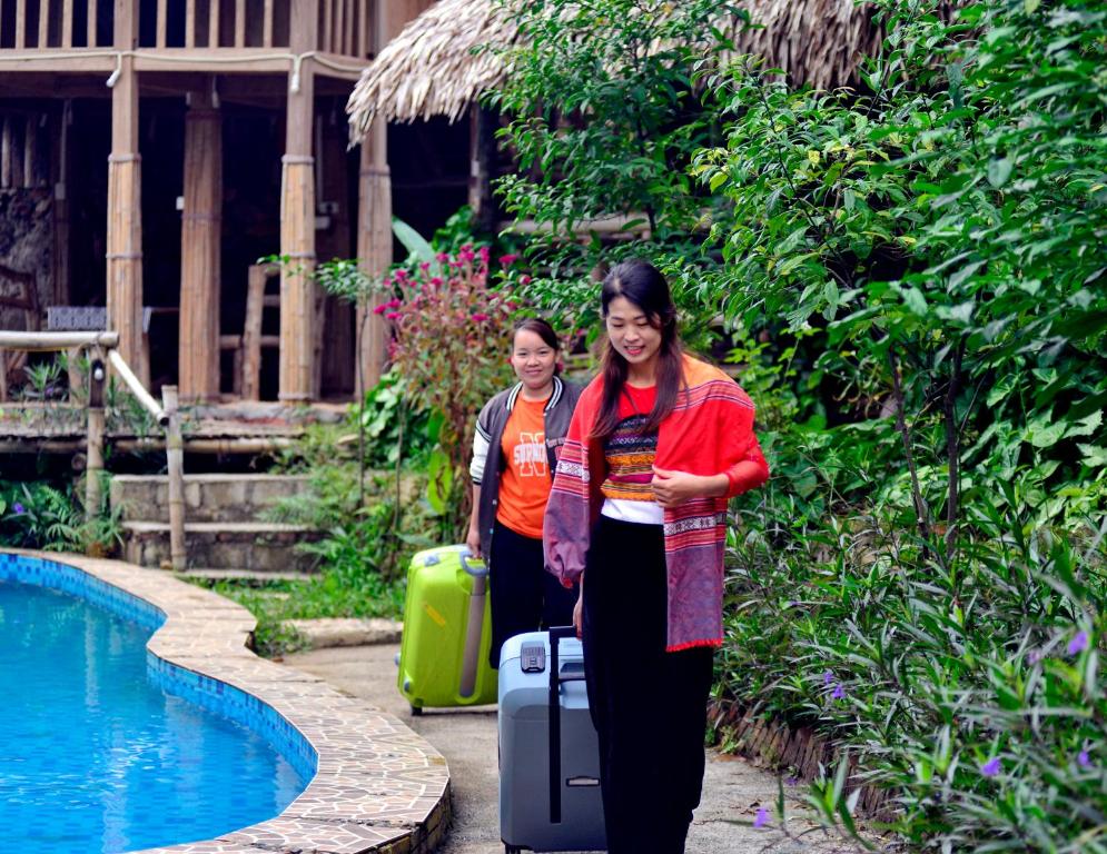 two women with luggage standing next to a pool at Duân Thảo homestay in Hòa Bình
