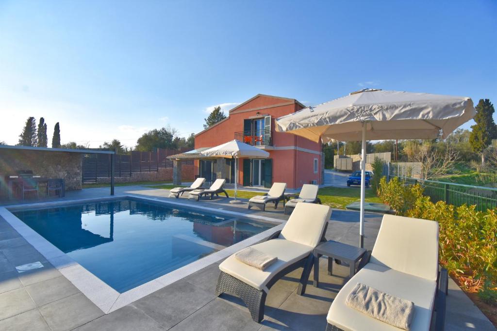 - une piscine avec des chaises et un parasol dans l'établissement Castelia Luxury Villas - Villa Agapi, à Ágios Ioánnis