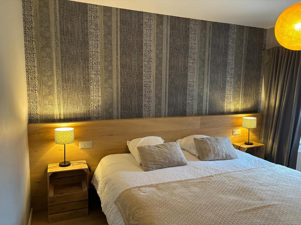una camera con un letto con due cuscini e due lampade di Auberge du Carrefour a Vielsalm