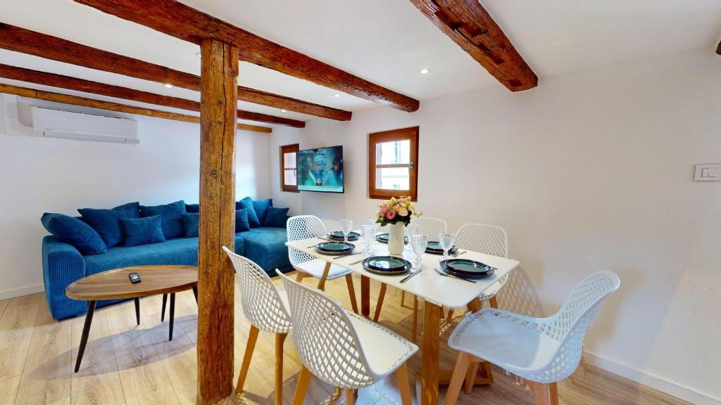ein Esszimmer mit einem Tisch und einem blauen Sofa in der Unterkunft Résidence de l'ancien relais in Colmar