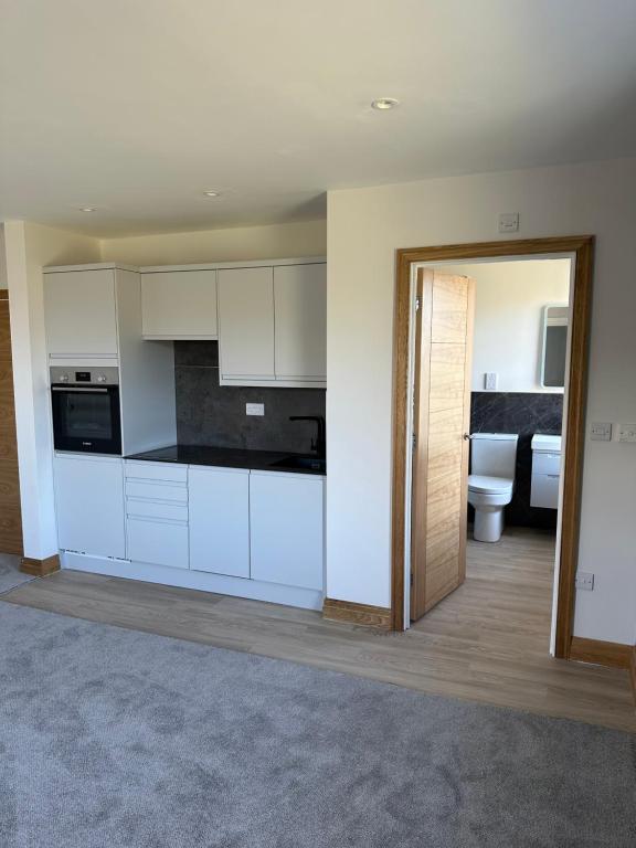 an empty kitchen with white cabinets and a bathroom at Grindal - Executive Apartment Hotel in St Bees