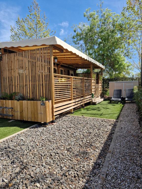 een houten paviljoen met 2 stoelen in een tuin bij Camping La Carabasse Vias-Plage - T4 Neuf, Tout Confort ! in Vias