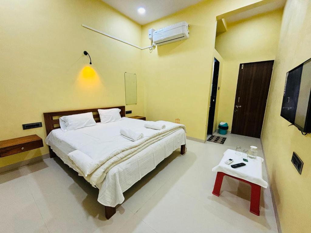 een slaapkamer met een groot wit bed en een tafel bij Kihim Paradise Beach & Resort in Alībāg