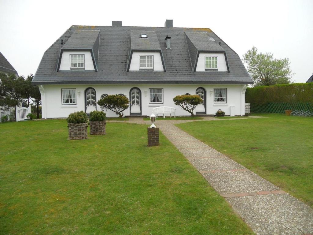 a large white house with a green yard at Ferienwohnung für 2 Personen ca 55 qm in Munkmarsch, Nordfriesische Inseln Sylt in Munkmarsch