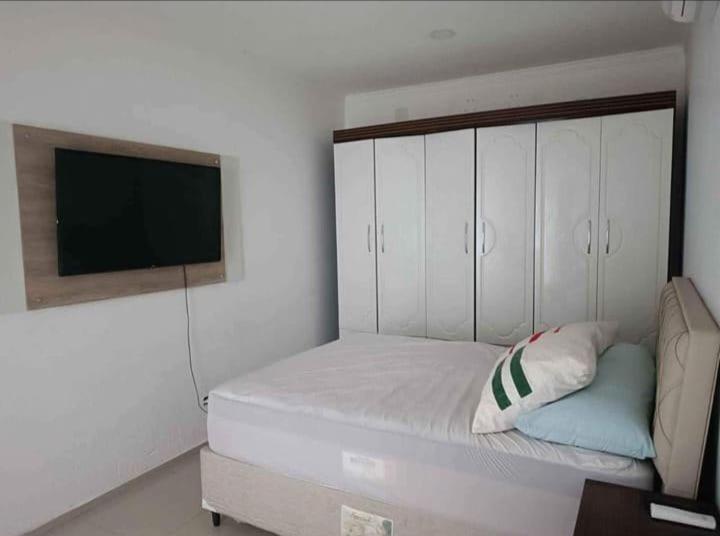 een slaapkamer met een bed en een flatscreen-tv bij Aluga-se casa com Piscina no Guarujá in Guarujá