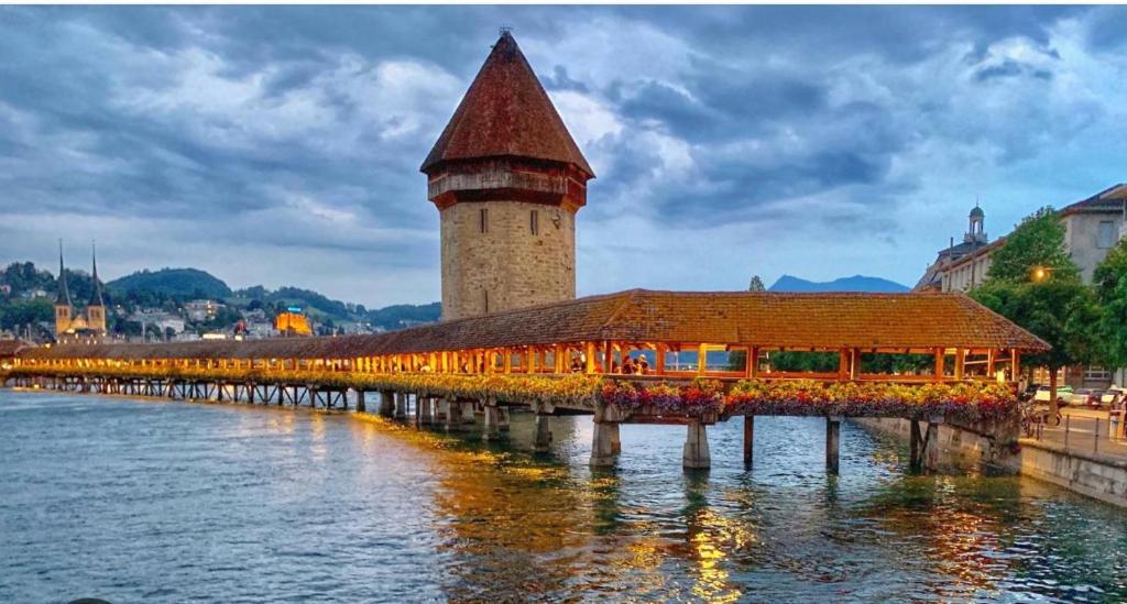 un puente sobre un río con una torre de reloj en 01 quarto de casal Os demais cômodos da casa serão de uso compartilhado en Lucerna