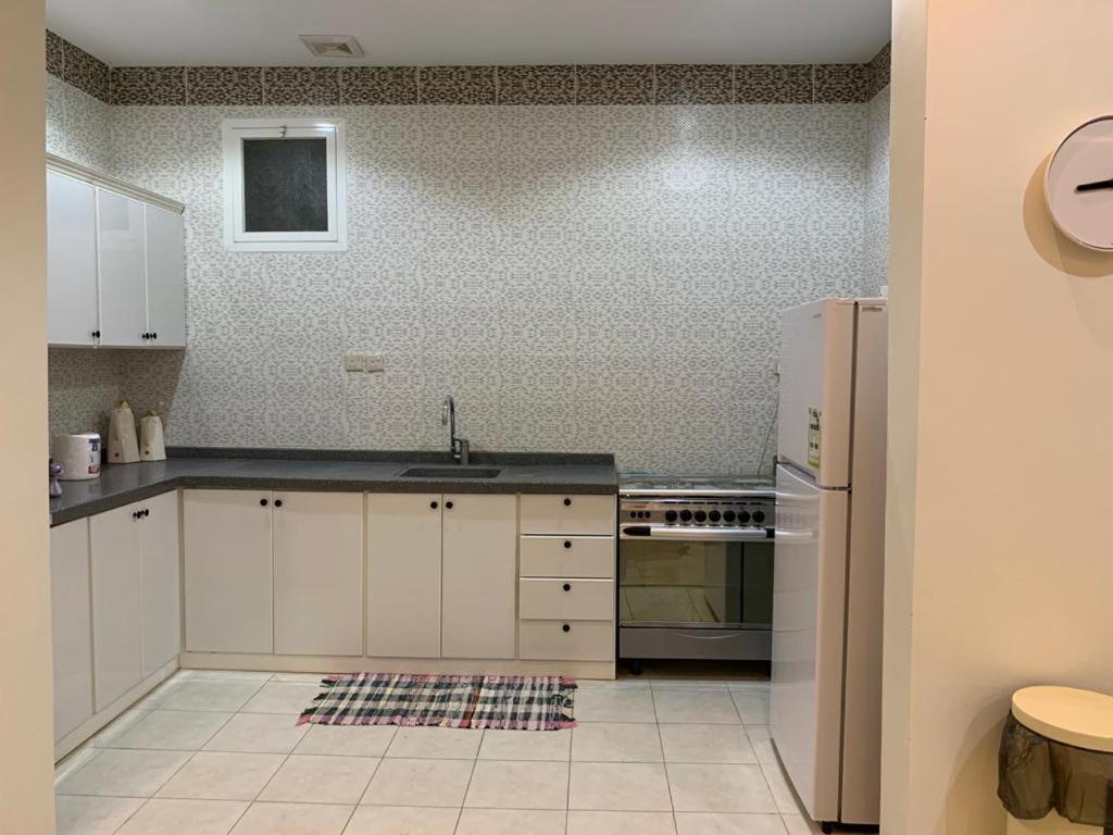 a kitchen with white cabinets and a stainless steel refrigerator at شاليهات أوريجامي in Buraydah