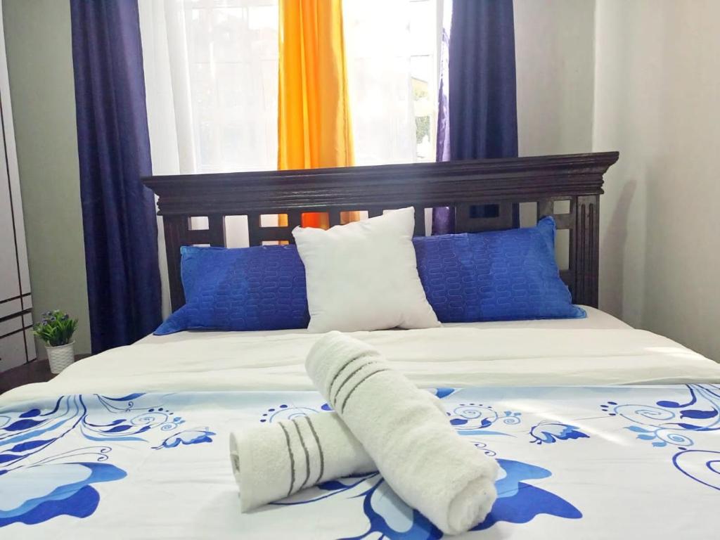a bed with blue and white blankets and pillows at Emerald Gardens Airbnb in Kitale