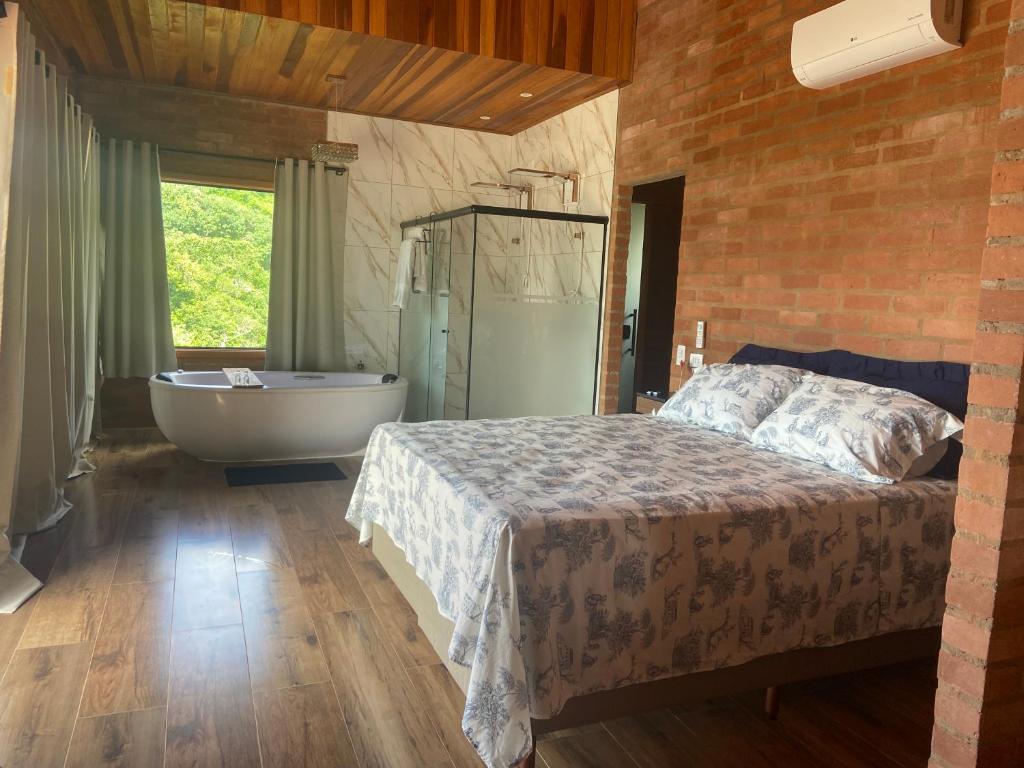1 dormitorio con cama, bañera y bañera en Chalé Magia do Serrano, en São Bento do Sapucaí