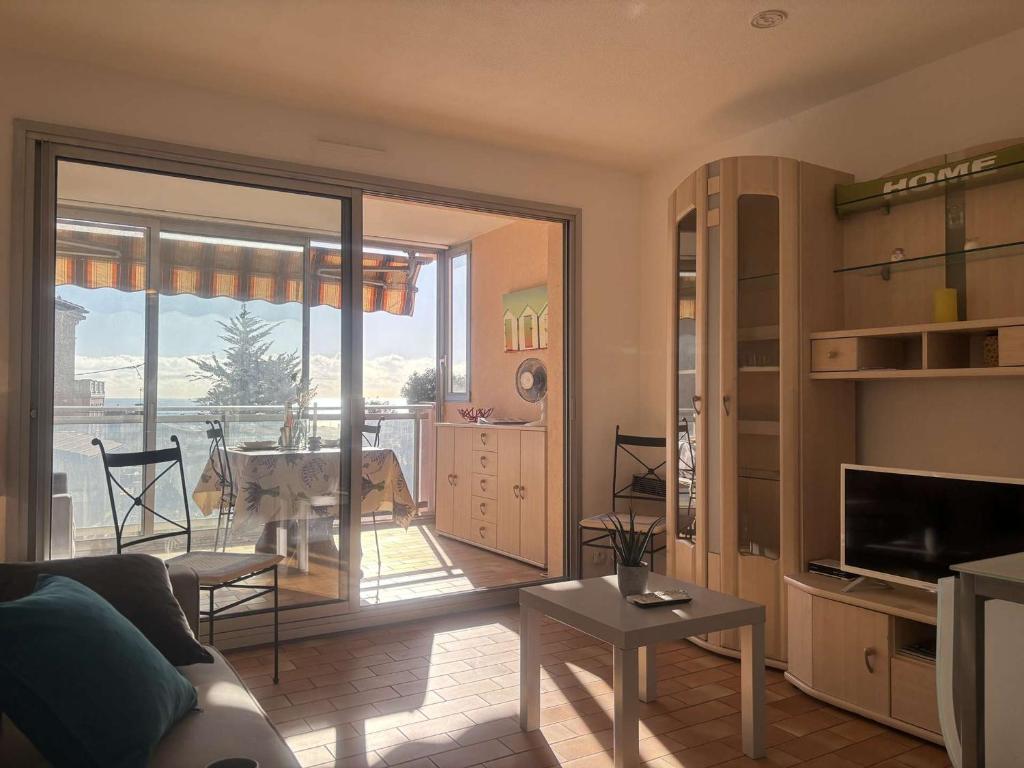 ein Wohnzimmer mit einer großen Glastür zu einem Balkon in der Unterkunft Appartement Golfe Juan, 1 pièce, 2 personnes - FR-1-252-62 in Golfe-Juan
