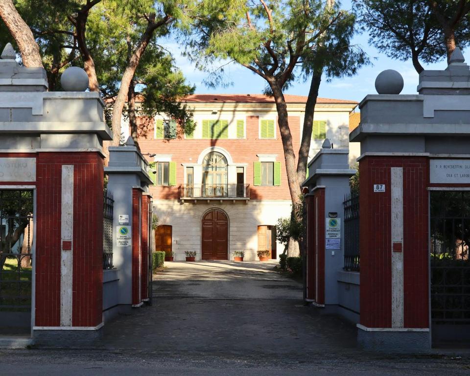 un vialetto che conduce a una casa con porte rosse e bianche di Ostello e Camere Private Prima Luce Foresteria a Giulianova