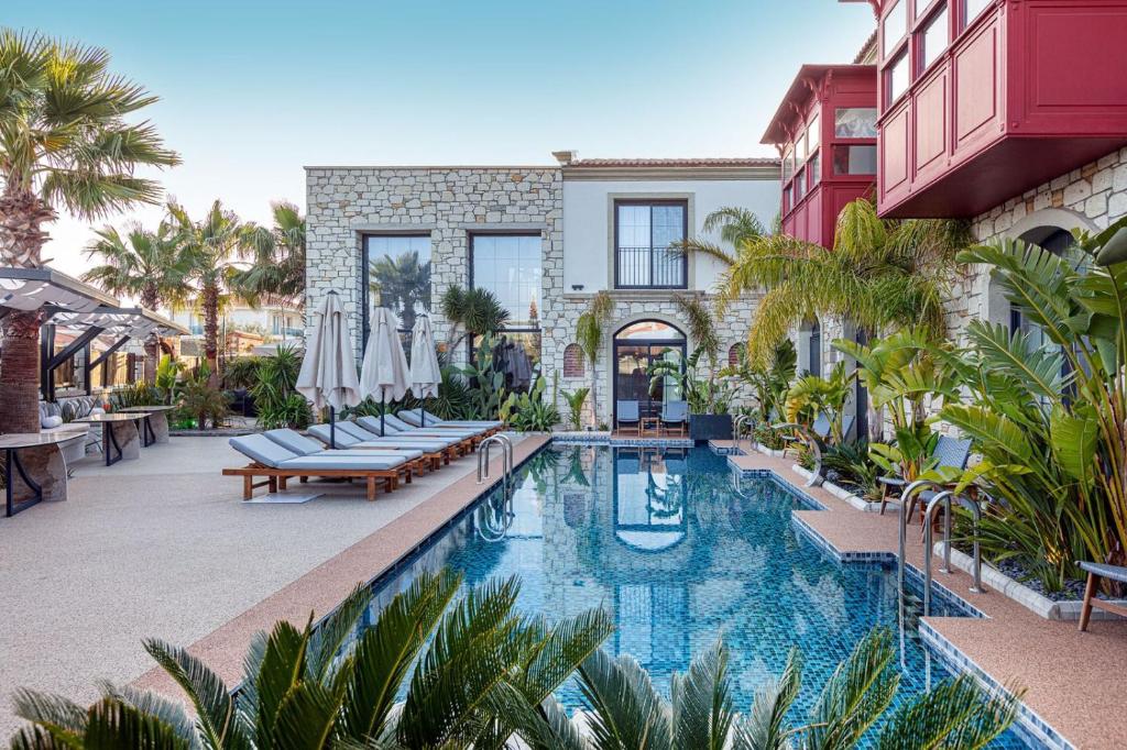 a pool with chairs and umbrellas next to a building at Dmira Alacati in Alaçatı