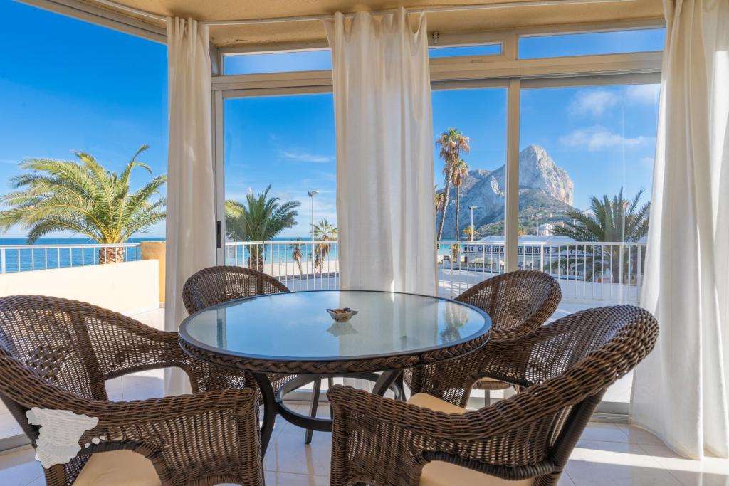 einen Glastisch und Stühle auf einem Balkon mit Blick auf den Strand in der Unterkunft CostaBlancaDreams Apartment Gran Sol in Calpe in Calpe