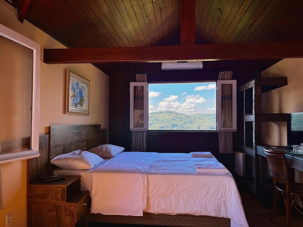 sypialnia z łóżkiem i dużym oknem w obiekcie Pousada Villa da Uva w mieście Gramado