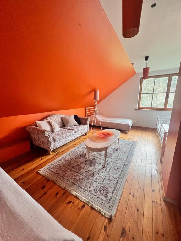 an orange room with a couch and a table at Farm hostel - The hause 1 in Elektrėnai